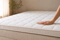Verkoelende topper Elea Cool van Wonello® op een boxspring, hand voelt het quilted oppervlak. In lichte beige slaapkamer