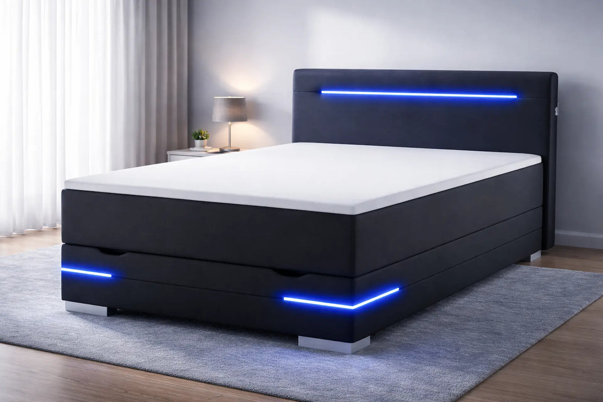 Zwart gestoffeerd boxspringbed met geïntegreerde blauwe LED-verlichting in hoofdbord en onderzijde, diagonaal geplaatst in een rustige, moderne slaapkamer met grijze tinten en zacht daglicht.