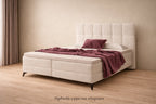 Boxspring Madison met aubergine plaid en kussen in lichte ruimte. Tekst: afgebeelde topper niet inbegrepen