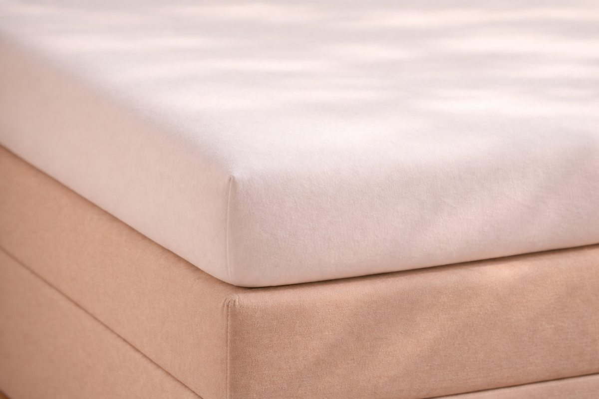 Detail van matras met topper erop met glad hoeslaken