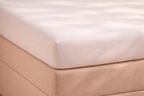 Detail van matras met topper erop met glad hoeslaken