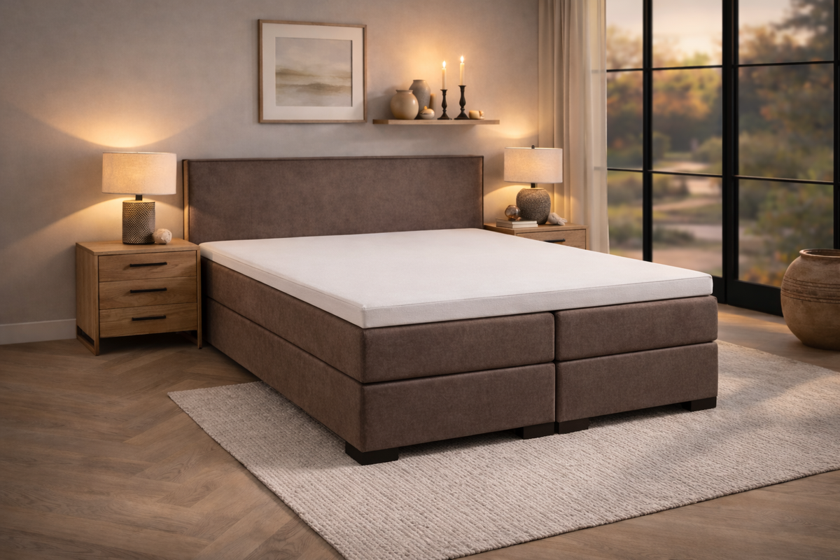 Slaapkamer in strijklicht met bruin bed en topper met hoeslaken
