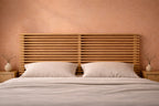 Detail hoofdbord tegen een terracotta wand, bed opgemaakt in off white 
