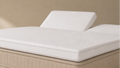 Split-topper op matras in beige omgeving. Topper heeft linker hoofdeind omhoog