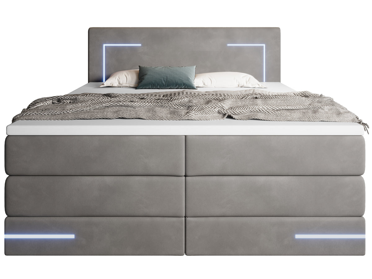 Vooraanzicht antraciet gestoffeerd bed met led-verlichting aan en op de topper een plaid en kussens.
