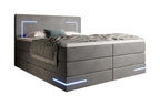 Diagonaal antraciet gestoffeerd bed met led-verlichting aan en op de topper een plaid en kussens.
